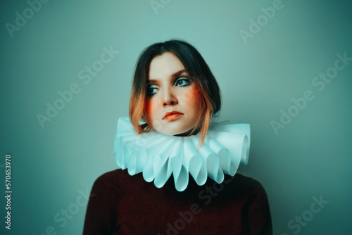 Portrait of a beautiful woman with a bright unusual makeup and a white jabot around her neck. The queen's clown costume.