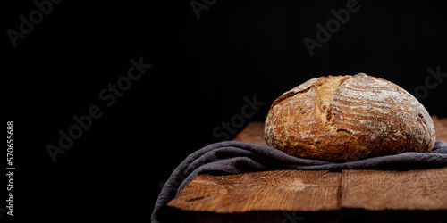 Fresh wheat rustic sourdough bread on a wooden table black background. Panoramic view, free space for text
