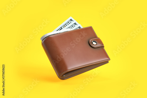 urse or wallet with money dollar bills on yellow background.