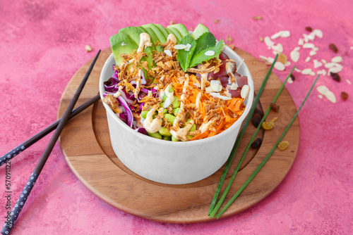 Tuna poke bowl (edamame beans, carrot, rice, avocado, red cabbage, edamame beans, chives) on the red background