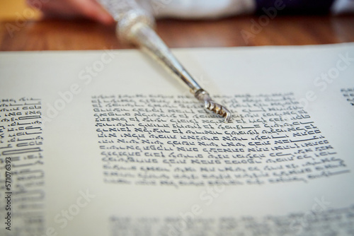 Close Up of Yad Pointing at Hebrew Letters in Torah Scroll
