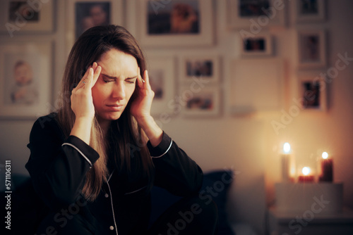 Stressed Woman Suffering a Migraine at Night before Going to Sleep. Unhappy adult person having headaches from insomnia 