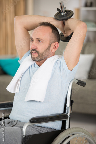 mature man in wheelchair working out with weights at home