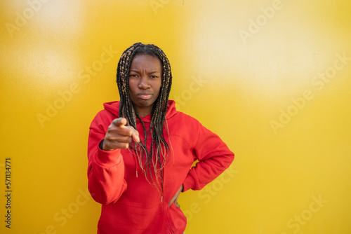 african woman pointing suspicious face yellow background