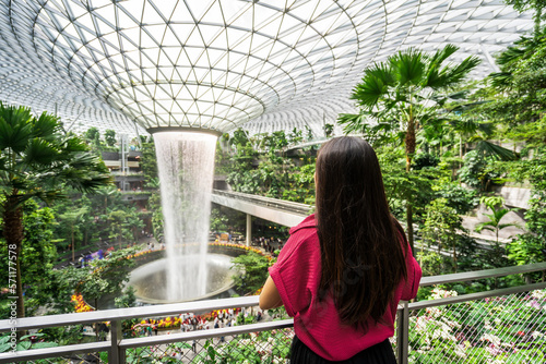 Young female tourist looking at the indoor waterfall in Changi Airport, Singapore