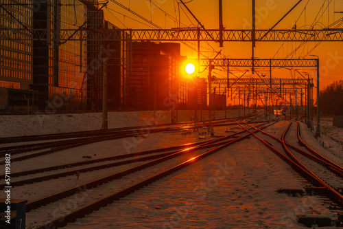 Jadący pociąg na torach kolejowych. Tory kolejowe zimą w zachodzącym słońcu. Odbicie na torach światła zachodzącego słońca