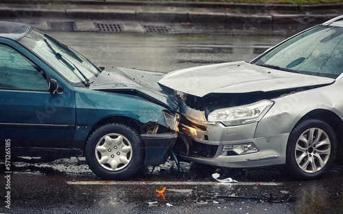 Car accident on wet road during rain, head on collision side view. Two cars damaged after head-on collision, car crash. Car crash on the street, damaged cars after collision. Traffic rules violation