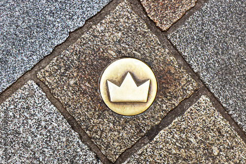 Top view of brass crown marker in cobblestone streets that shows location of the coronation walk, Bratislava, Slovakia. Old town