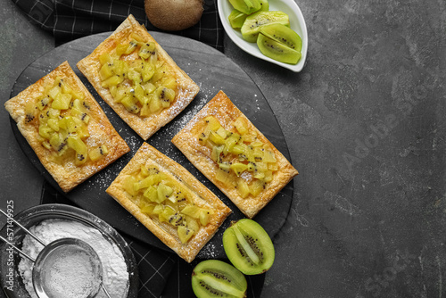 Fresh tasty puff pastry with sugar powder and kiwi served on grey table, flat lay. Space for text