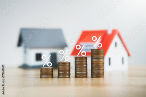 the percentage symbol for increasing interest rates on stacks of coins and the model house. Interest rates increase, home loan, mortgage, house tax. investment and asset management concept