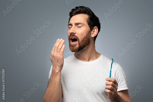Middle aged man holding hand near mouth and checking breath freshness, worrying about poor oral hygiene