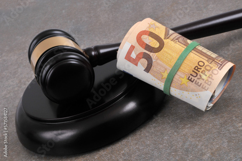Concept de frais de justice avec avec un marteau de juge et une liasse de billets en euros en gros plan sur fond gris