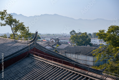 Scenic view of traditional Chinese tile roofs of houses in the Old Town of Lijiang, Yunnan province, China. Mountains in background. The Old Town of Lijiang is a popular tourist destination of Asia.
