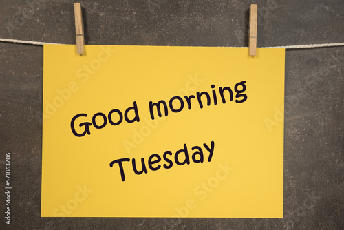 Napis Good morning Tuesday na wiszącej żółtej kartce na ciemnym tle