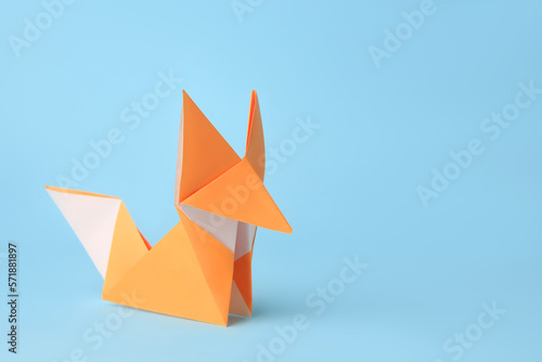 Origami art. Handmade orange paper fox on light blue background, space for text