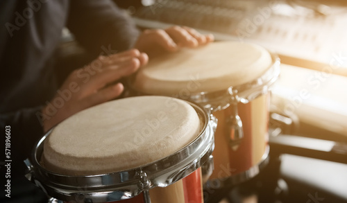 Musician playing hand Bongo Drums indoors closeup. Man with traditional ethnic folk music instrument