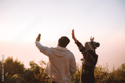 Two people traveller using smartphone selfie together with nature view at sunrise time. Travel and recreation concept on vacations.