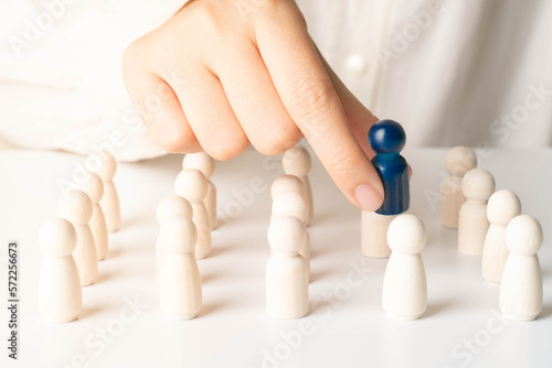 Hands take blue wooden figure out of crowd. Concept of rare disease, LGBTQ, virus epidemic, human resource, staff recruitment, talent, leadership and unique.