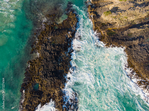 An aerial view of sea waves crashing on coastal rocks in Dunedin, New Zealand
