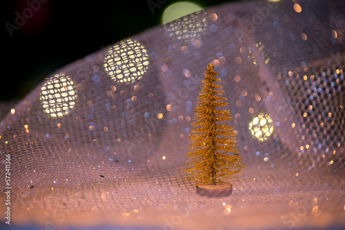 Golden decorative Christmas tree and sparkling bokeh against the background of a blurred Christmas tree in lights