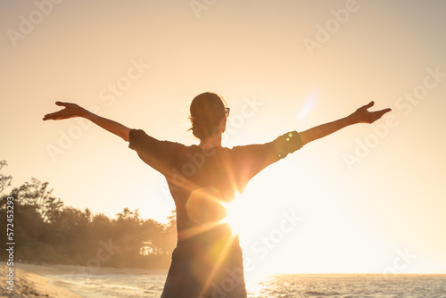 Young female feeling grateful, joyful standing outdoors in the sunrise 