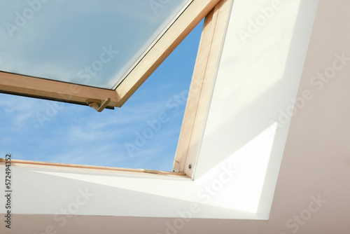 Open skylight roof window on slanted ceiling in attic room