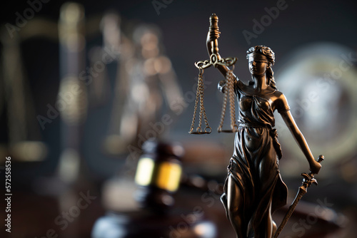 Law and justice concept. War crimes. Gavel and Themis sculpture in lawyers office. Gray bokeh background.