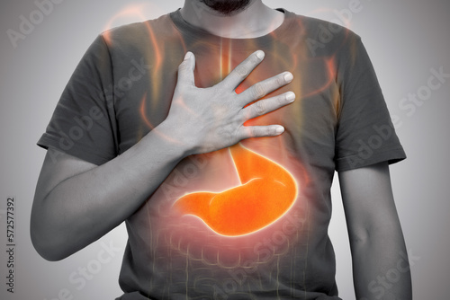 A man burning sensation in chest from acid reflux on gray background.