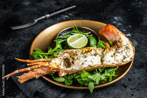 Grilled Spiny lobster with salad on a plate. Black background. Top view