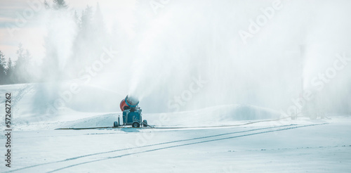 Snow cannon in winter mountains. Snow-gun spraying artificial ice crystals. Machine making snow. Strbske pleso (Strbske lake) ski resort with snow.
