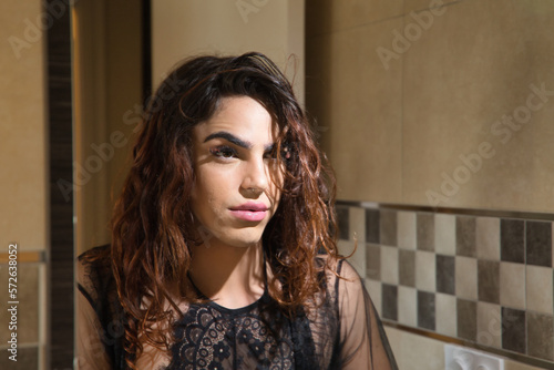 Young transgender girl, looking at herself in the mirror after having make up, with serious and worried gesture. Concept transgender, lgtbi, homosexuality, gay, diversity.