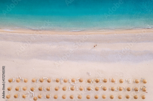 Sun umbrellas rows and sunbeds Myrtos Beach unique turquoise water seashore with a bright white pebbles often proclaimed as one of best beaches in Greece. Kefalonia island aerial background photo.