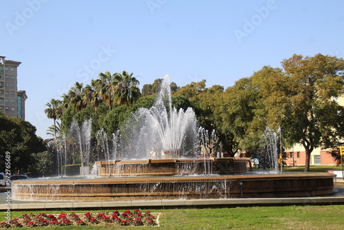 Central fountain, with several water jets and flowers on the lawn