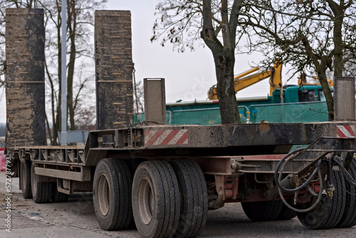 Duża i potężna naczepa - laweta , bardzo zabłocona , do przewozu ciężkich maszyn budowlanych na plac budowy . 