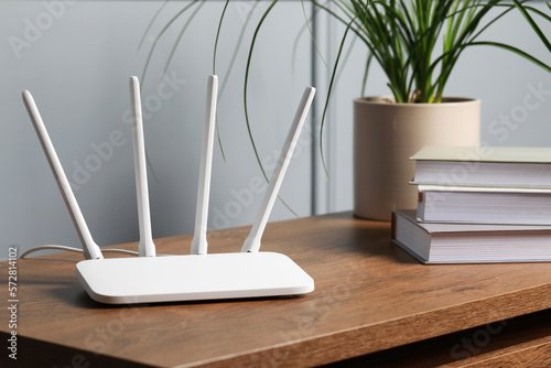 New white Wi-Fi router on wooden table indoors