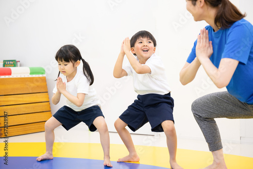 室内で運動をする子供たちと先生