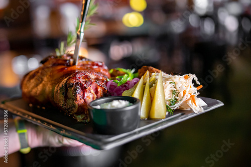 Waiter hold plate with Roasted pork knuckle in restaurant