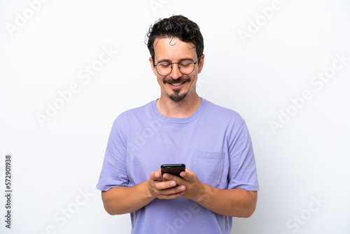 Young man with moustache isolated on white background sending a message with the mobile