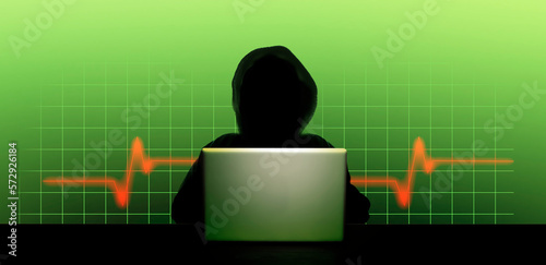 Dunkle Person mit Kapuze als Silhouette vor einem geöffneten Laptop und digitalem Hintergrund