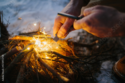 Male hand starts fire with magnesium fire steel, fire striker.