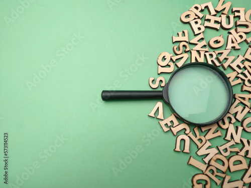 Wooden word and magnifying glass on a green background