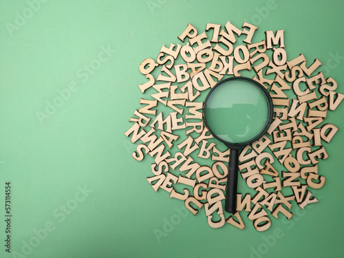 Wooden word and magnifying glass on a green background