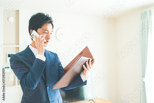 スマートフォンで電話をする不動産営業マンの若い男性