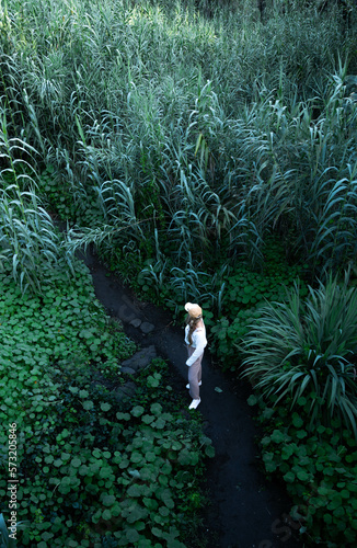 Blonde woman standing surrounded plants in the middle of the nature