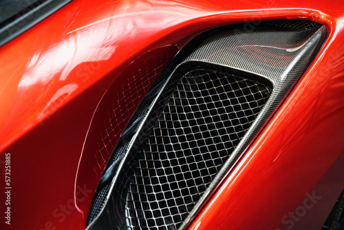 detail of sport car with red metal hood and black air flow intake ornament