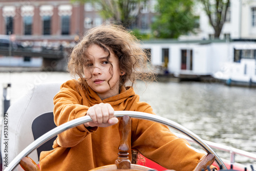 A girl at the wheel of a boat on a canal in Amsterdam