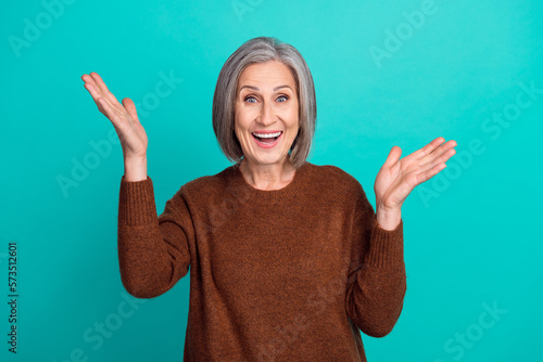 Photo of positive joyful lovely senior lady wear brown trendy clothes raise arms celebrate victory isolated on cyan color background