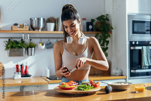 Fintess woman making a healthy poke bowl in the kitchen at home.