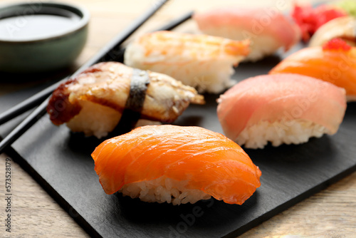 Serving board with delicious nigiri sushi and soy sauce on wooden table, closeup
