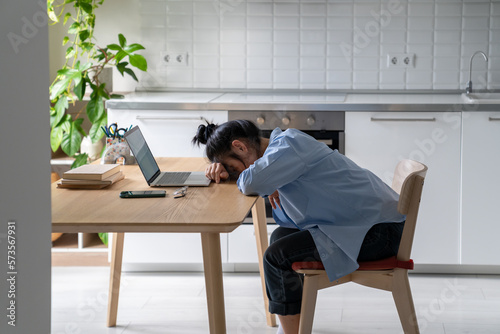 Tired Asian freelancer woman was exhausted from hard work at laptop take nap on table from overwork. High quality photo